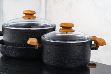 Black cookware on induction stove against grey wall