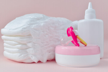 Baby diapers and nipple, cream and powder close-up.