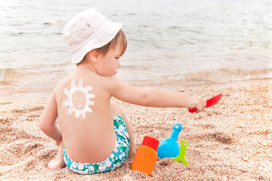 The sun drawing sunscreen on baby (boy) back. Beach.