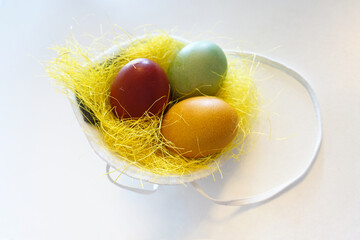 Tree colorful painted eggs in anti-virus mask. Medicine mask like yellow nest with easter eggs inside. White background. Corona during easter time
