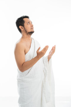 Muslim man praying while standing in white traditional clothes open his arm