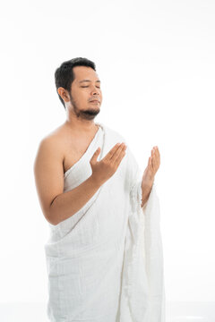 Muslim man praying while standing in white traditional clothes open his arm