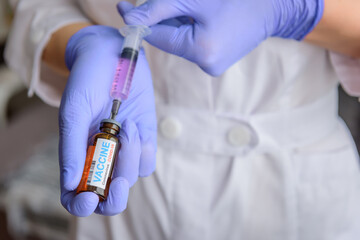 Doctor's hands in medical gloves filling a syringe with the covid 19 vaccine. Nurse holding syringe and new coronavirus vaccine. Healthcare And Medicine concept.