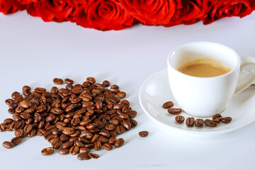 Cup of coffee and a bouquet of red roses. Coffee beans scattered on the table. Good morning.