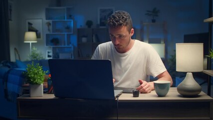Young handsome male designer draws with a pen on a tablet at home in the living room