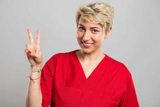 Portrait of young attractive female nurse showing peace gesture