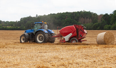 Obraz premium traktor making hay bales in a field - hay bale making machine