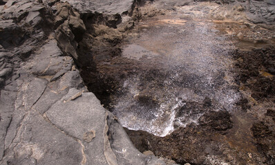 North coast of Gran Canaria, lava fields of Banaderos area, grey textured lava from eruption of Montana de Arucas, breaking waves