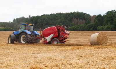 Obraz premium traktor making hay bales in a field - hay bale making machine