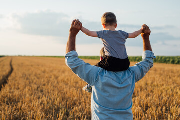 farmer holding his grandson standing in wheat field
