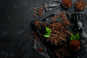 Coffee. Roasted fragrant coffee beans and coffee maker on a black stone background. Top view. Free space for your text.