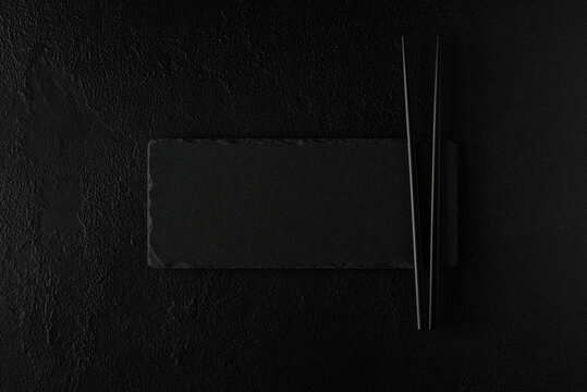 Empty black slate plate with chopstick on dark Background. Flat Lay. Top view. Mock-up