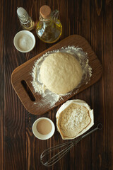Baking in rural kitchen. Dough and recipe ingredients on vintage brown wooden table. Top view. Rustic background