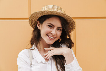 Portrait of cheerful woman in straw hat laughing and looking at camera