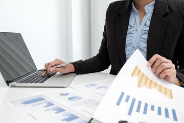 The hands of a male businesswoman are analyzing and calculating the annual income and expenses in a financial graph that shows results To summarize balances overall in office