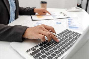 The hands of a male businesswoman are analyzing and calculating the annual income and expenses in a financial graph that shows results To summarize balances overall in office