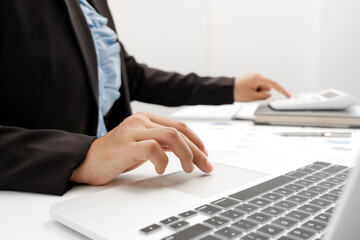 The hands of a male businesswoman use the calculator are analyzing and calculating the annual income and expenses in a financial graph that shows results To summarize balances overall in office