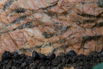 raw pink granite with streaks lies on the ground close up