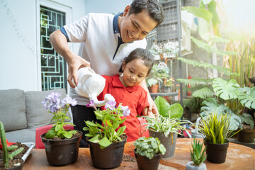 father and daughter smiled happily while holding a watering can to water the potted plants