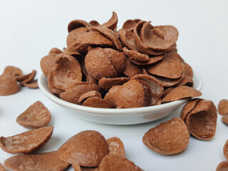 Cocoa crunch cereal or cornflakes, on a small plate. Isolated in white background.
