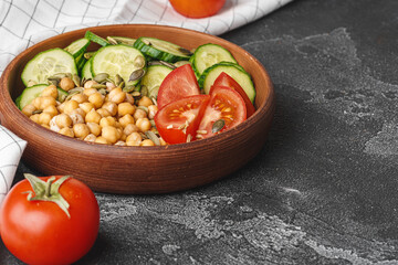 Clay plate of chickpeas and cut cucumbers and tomatoes. Healthy eating