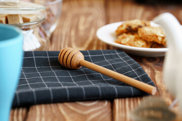 Wooden honey dipper on kitchen table with kitchenware