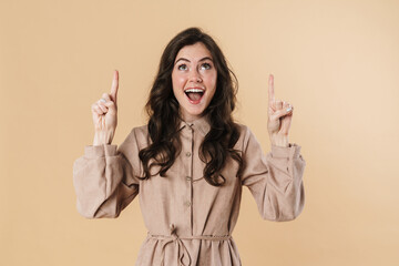 Image of excited attractive woman smiling and pointing fingers upward