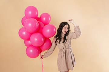Image of excited cute woman laughing and dancing with pink balloons
