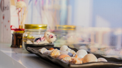 Set of decorations consisting of seashells standing on the window sill with a blurred background