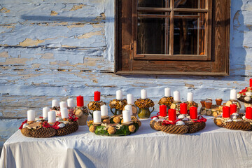 Christmas wreaths with candles braided from tree cones on table at wooden cottage...