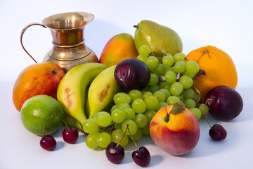 Assortment of fresh ripe exotic fruits and a copper jug ​​on a light background. Healthy eating concept.