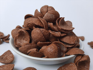 Cocoa crunch cereal or cornflakes, on a small plate. Isolated in white background.