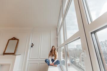 beautiful girl sitting on the window and smiling