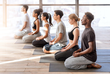 Wellness Concept. Young sporty people in yoga class making meditation exercises together - Powered by Adobe