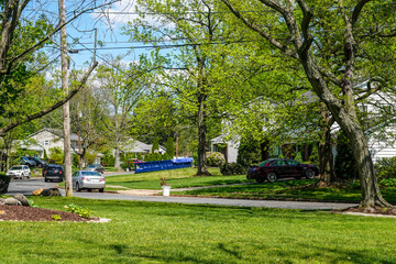 A long blue dumpster in the driveway of a house on a residential street that is being renovated