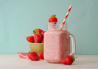 Strawberry smoothie or milkshake in mason jar on 
light wood table. Healthy food for breakfast and snack.