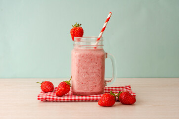 Strawberry smoothie or milkshake in mason jar on 
light wood table. Healthy food for breakfast and snack.