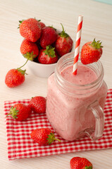 Glass with tasty strawberry smoothie on wooden table