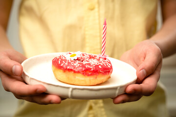 Candle in a donut on a white plate holding a boy