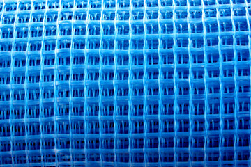 The blue reinforced mesh rolled into a roll lies on the ground. Construction resource to strengthen...