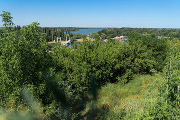 Fototapeta na wymiar Panorama of top view of the river and the bridge, summer sunny day, bright natural colors of green trees