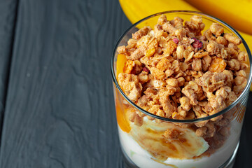 Tasty breakfast with granola, yoghurt and fruits in a glass bowl