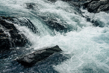 Big rapids of powerful mountain river. Beautiful background with azure water in fast river. Frozen...