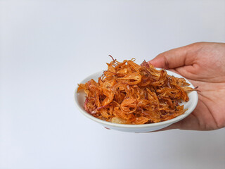Heap of fried onion crisp in a small plate. Isolated in white background.