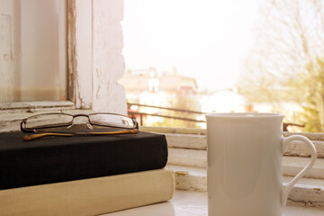 Black and white books, glasses and cup of tea on the windowsill. Reading books
