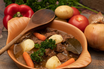 Beef goulash stewed with potatoes, carrots, and spices in a ceramic pot