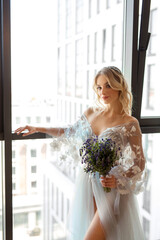 beautiful young woman in a delicate dress with makeup and hairstyle at home in the interior