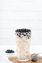 Bubble milk tea with tapioca pearl topping, famous Taiwanese drink on white wooden table background in drinking glass, close up, copy space