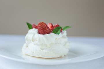 Pavlova meringue cake with whipped cream, fresh strawberry and mint on the top. Summer dessert. Selective focus.