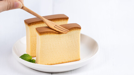 Castella (kasutera) - Beautiful delicious Japanese sliced sponge cake food on white plate over rustic white wooden table, close up, copy space design concept.